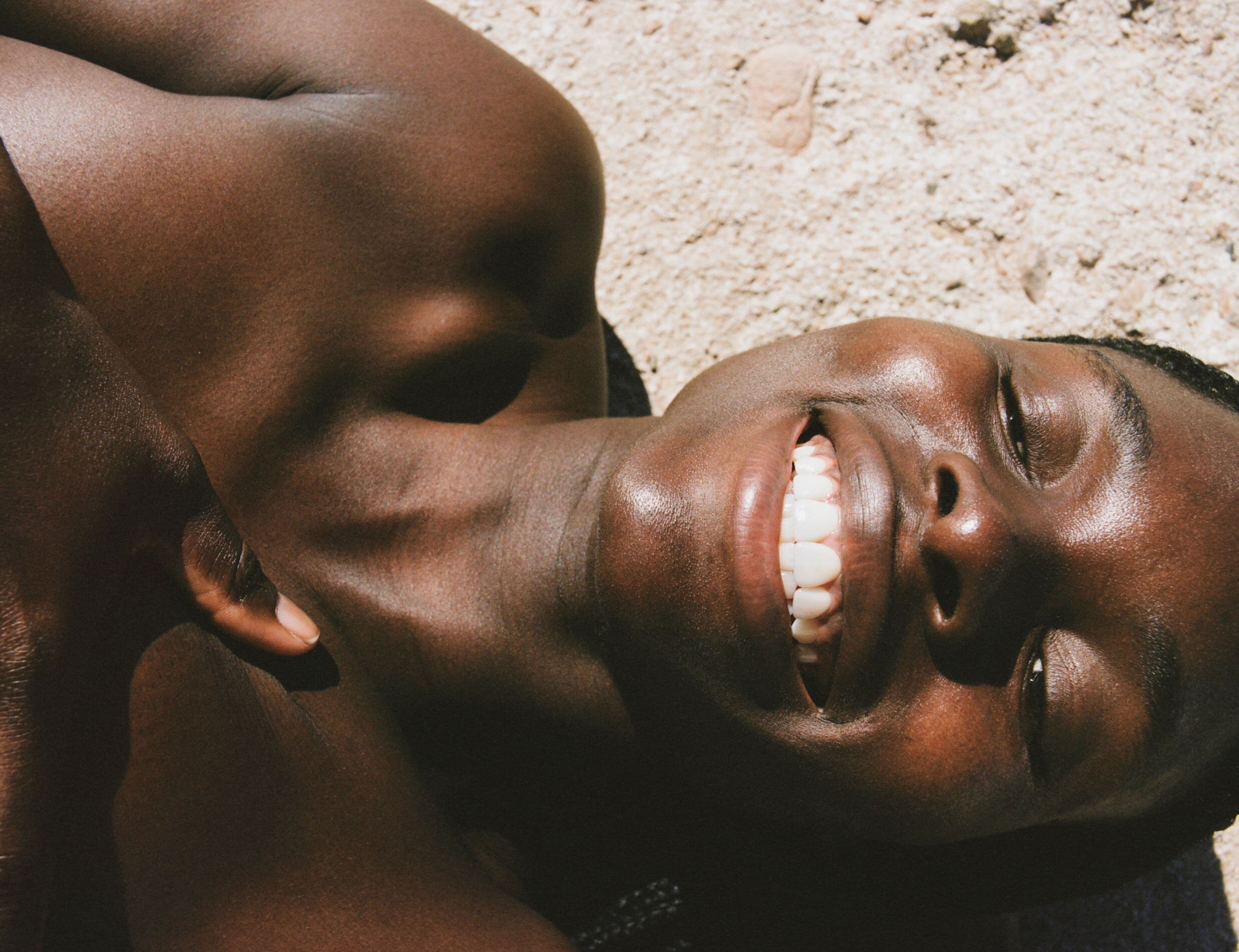 A woman smiling laying down on white bright rock with her hand on her heart